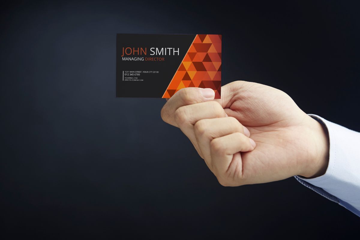 A person holding back side of a business card.