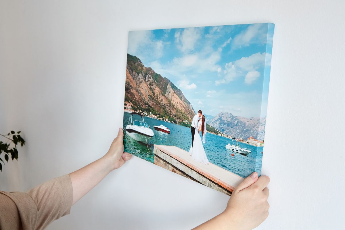 A person holding personal photograph of metal and acrylic prints try to hang it on wall