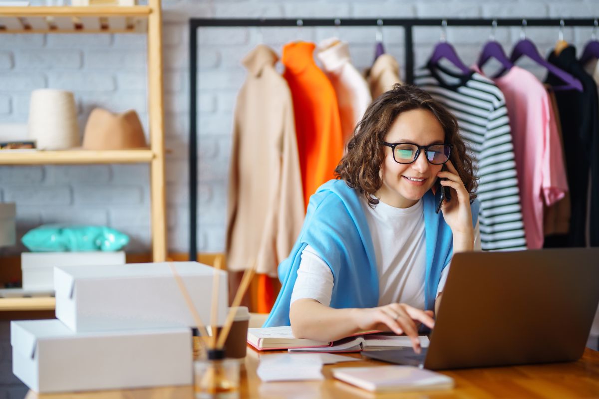 A woman working on a laptop while on the phone to scale her dropship business on shopify