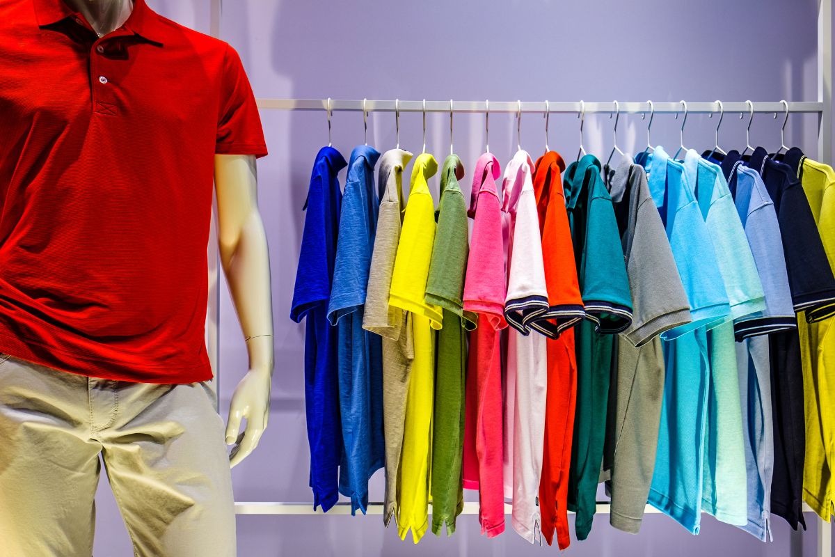 Variety of shirts hanged at the shop for the selling purpose with a mannequin dressed with shirt and pant