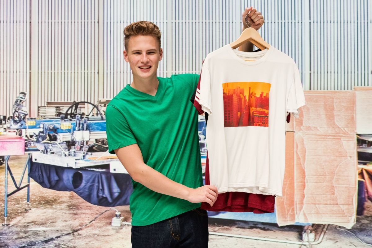A guy showing a t shirt with a print just in front of the t shirt