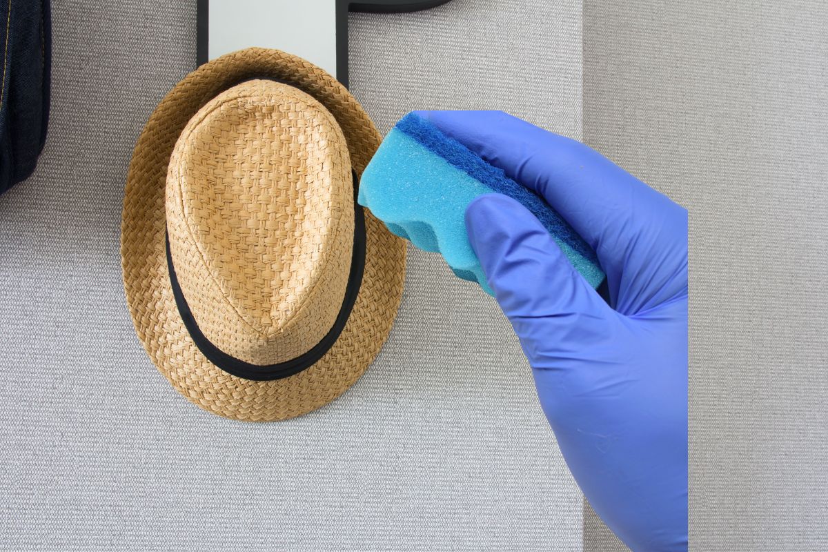 A hand delicately scrubs the hat to clean it thoroughly