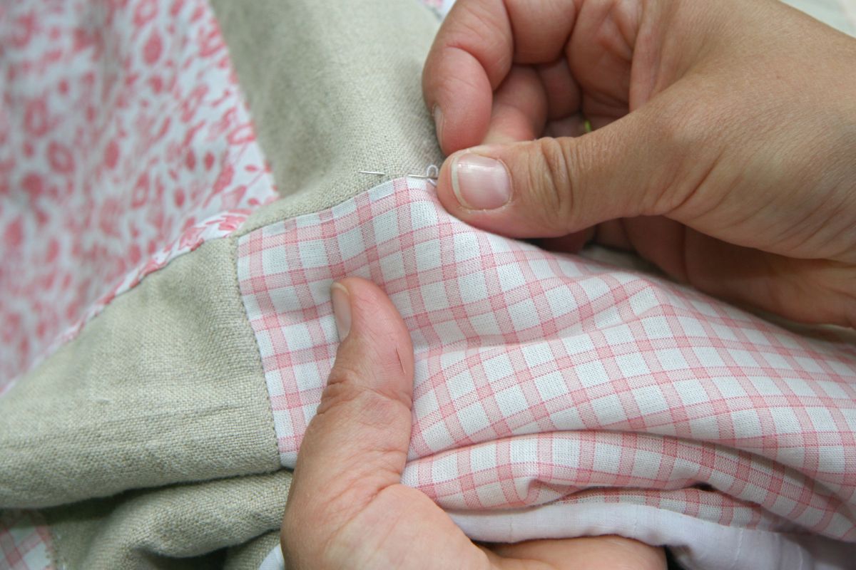 A lady sewing fabric part on a cloth