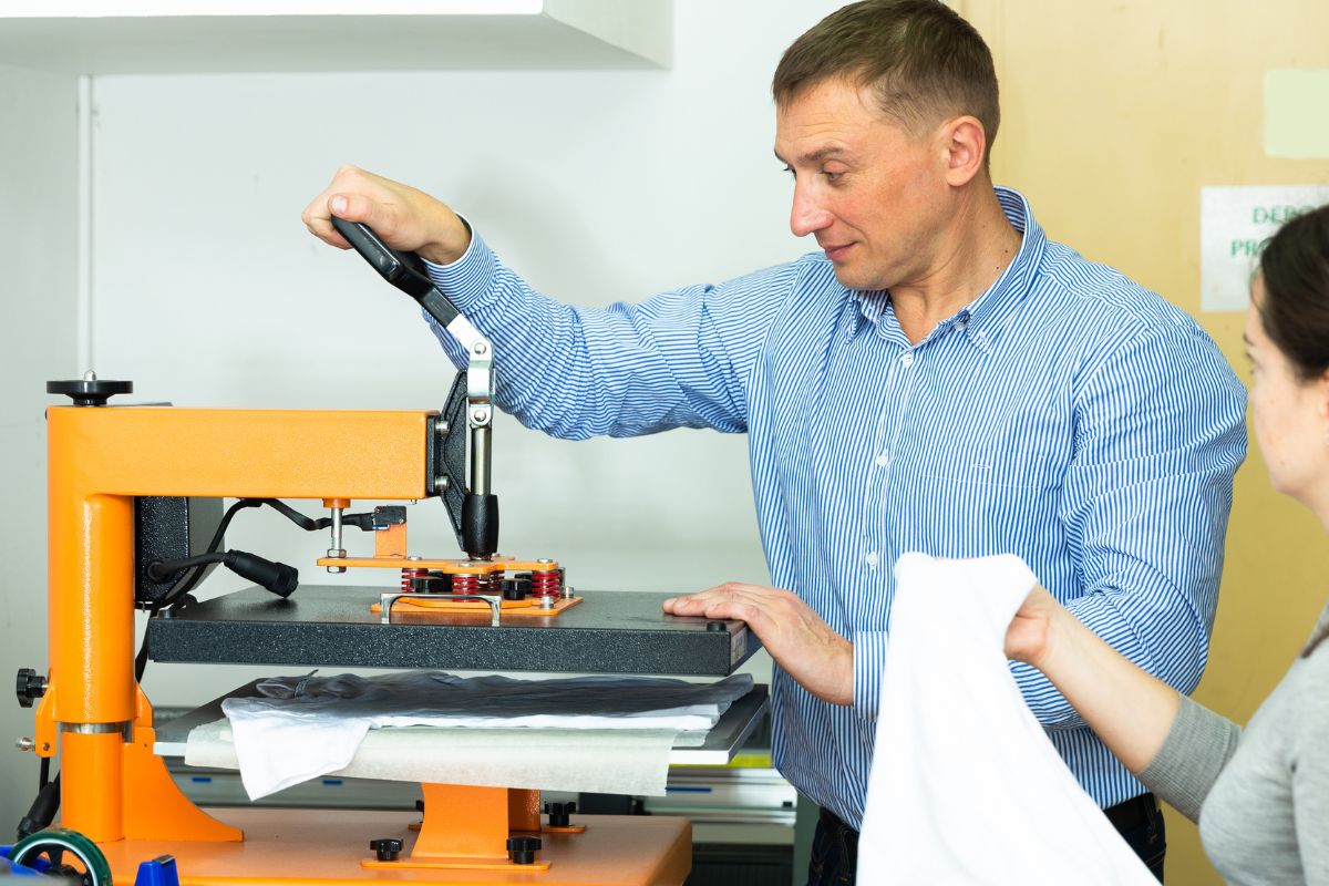 A person printing t shirt under a machine