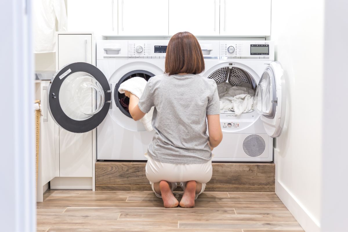 A woman loading printed T shirts into the washing machine for a wash