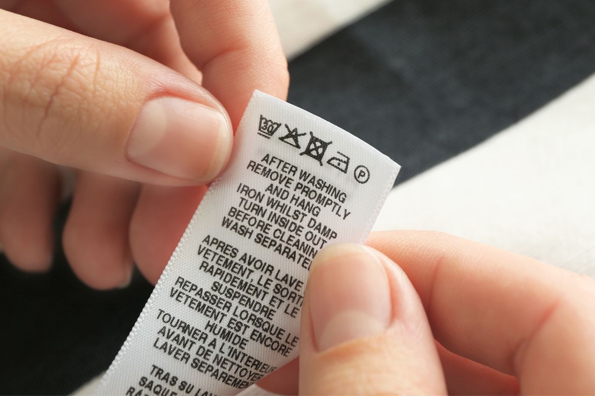 Before washing a hat a person is diligently reading the washing instruction tag
