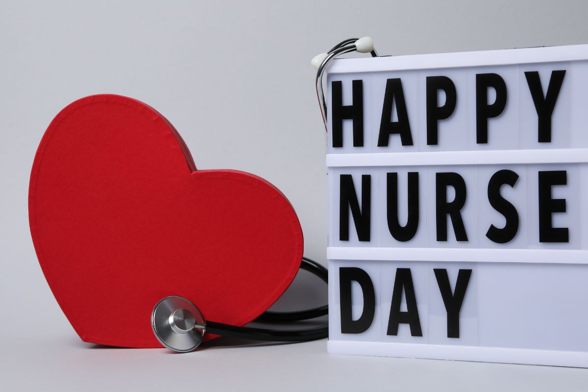 A 3d board with happy nurse day written on it with a stethoscope and a heart shaped model with it.