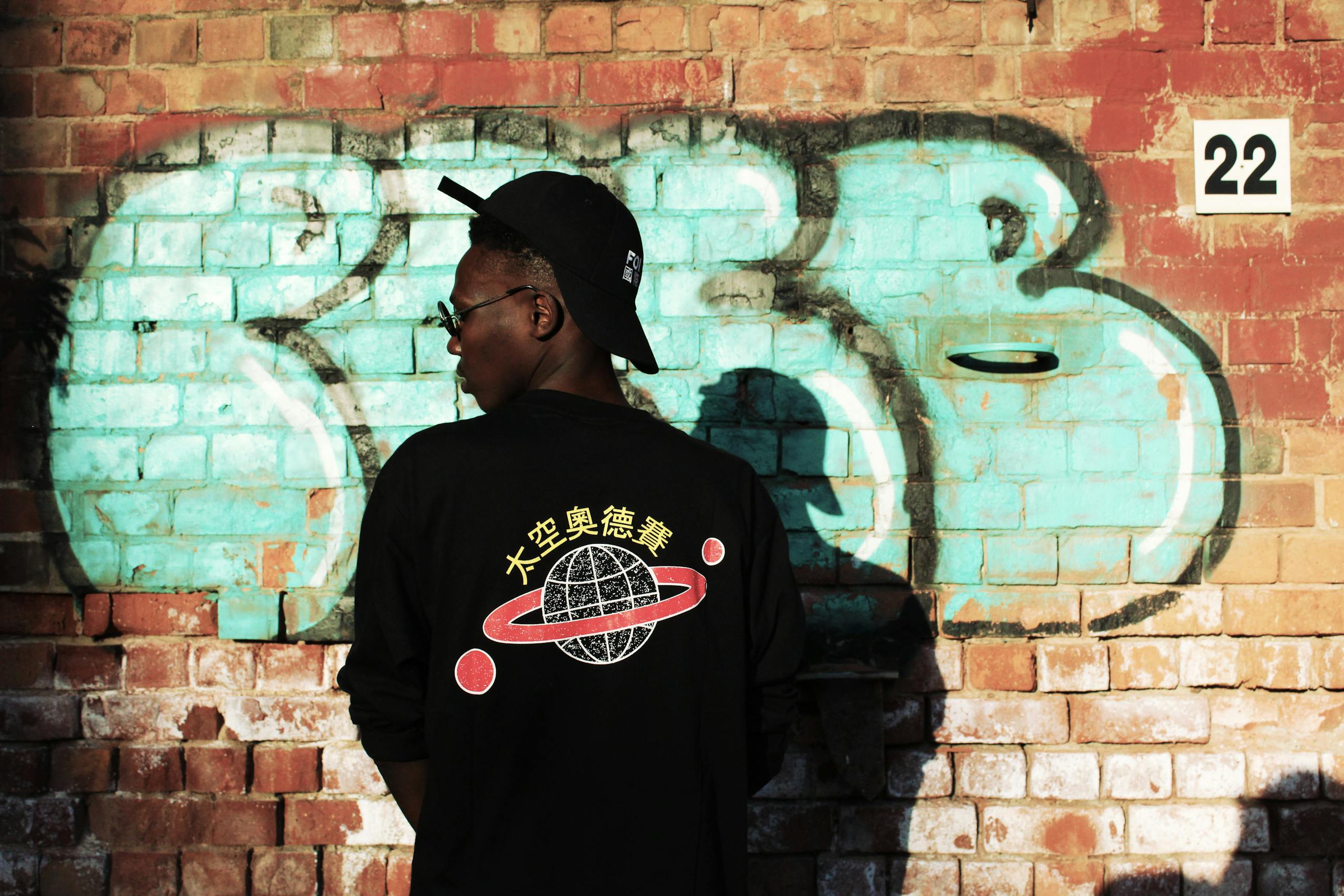 Man Wearing Black Long-sleeved Shirt Stands Near Red Wall