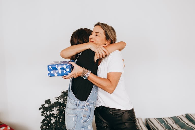 Two women hugging each other in a room with a christmas present