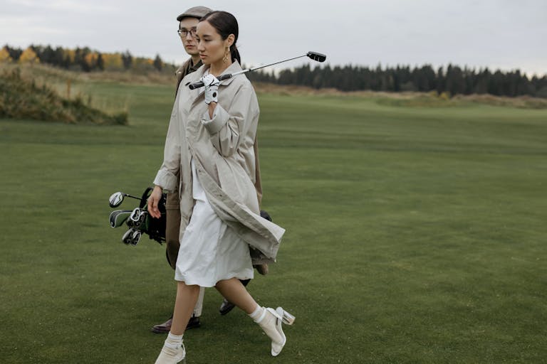 Woman in White Coat Holding Black Dslr Camera on Green Grass Field