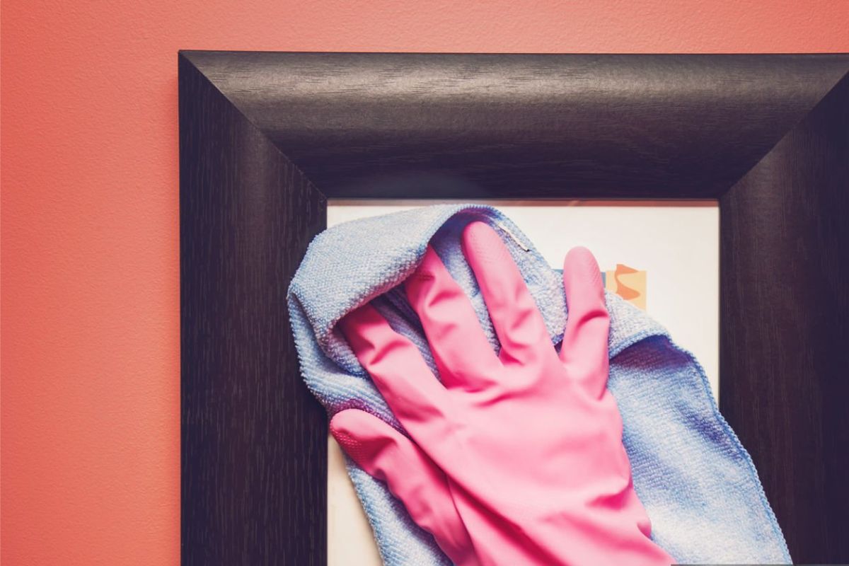 A lady cleaning a photo frame after adjusting photo in it.