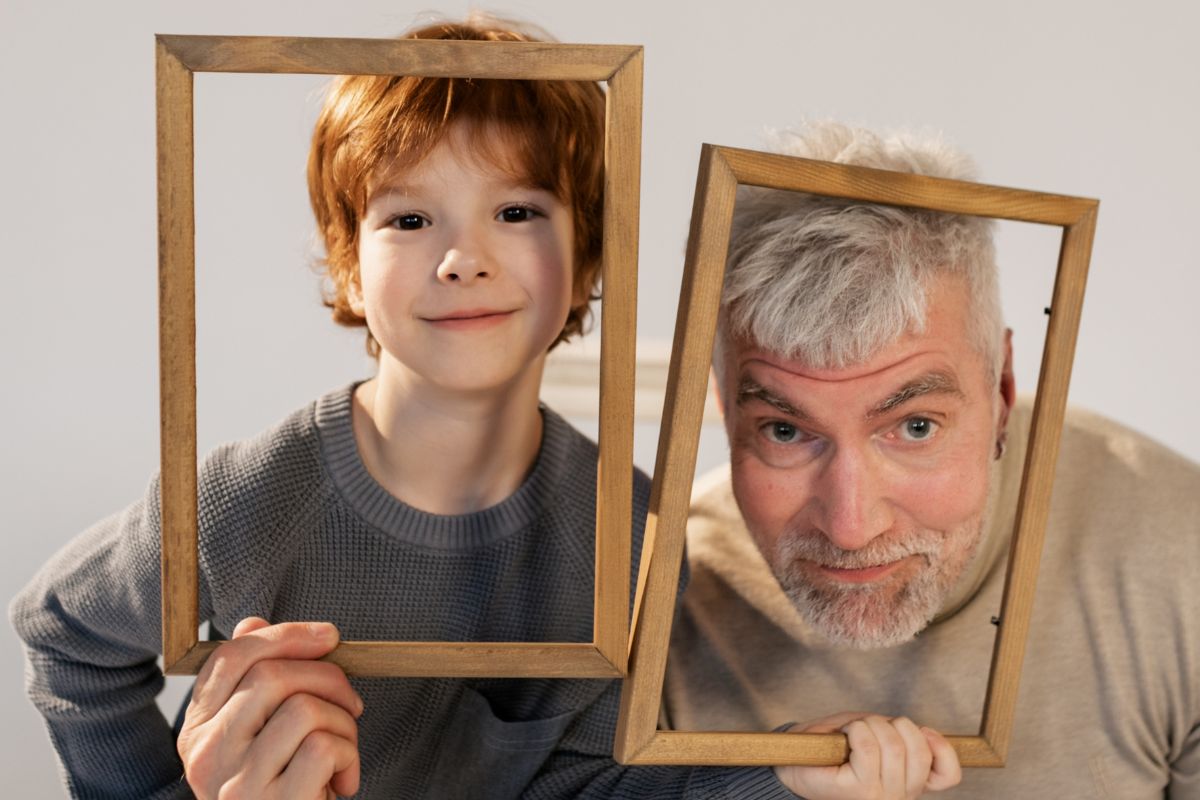 Grandfather and grandson clicking photo after making photo frames with each other.