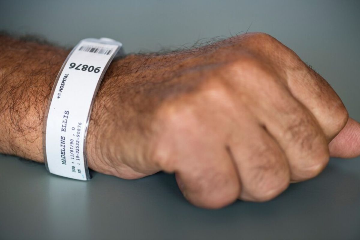 A person wearing wristband with his information written on it